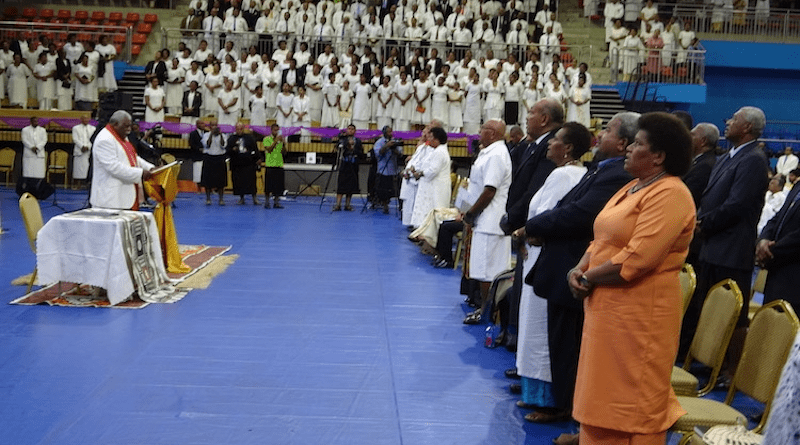 Rev Ili Vunisuwai praying for a united Fiji with the church choir in the background. Credit: Kalinga Seneviratne