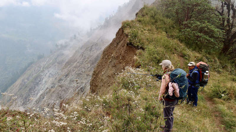 Tourists in October 2023 looking at mountain slopes affected by a slandslide along the Kanchenjunga Trek in Nepal . Most natural landslides are triggered by earthquakes or rainfall, or a combination of both. Copyright: Bruno Rijsman (CC BY 2.0). This photo has been cropped.