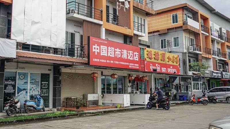 A motorcyclist parks in front of business advertising in Chinese in Thailand’s Hang Dong district in Chiang Mai province. Photo Credit: Kanokphorn Janploy/BenarNews